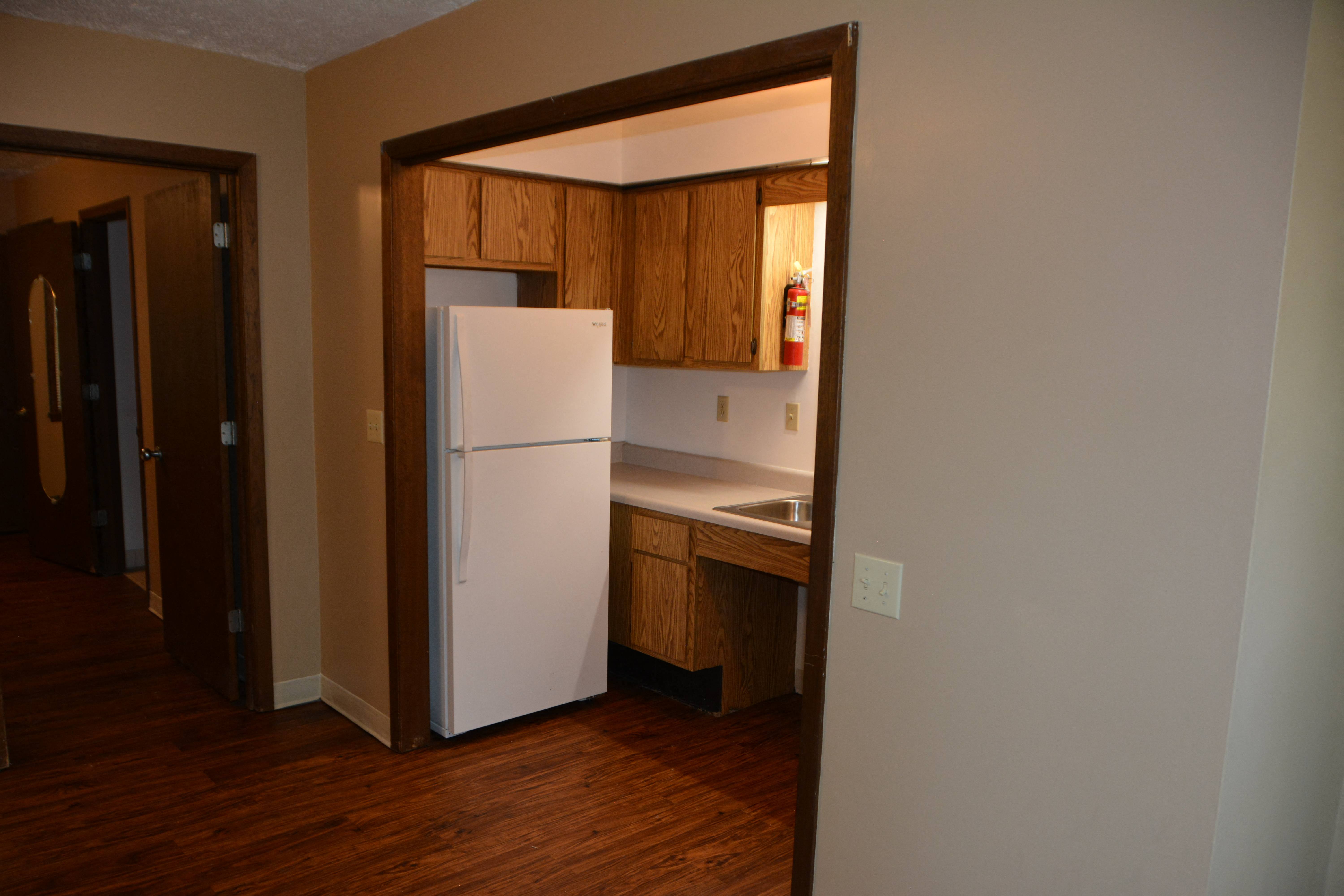 a kitchen with a white refrigerator and wooden cabinets
